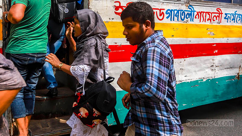 ঢাকার শাহবাগ মোড়ে শনিবার দুপুরে চলন্ত বাসে ঝুঁকি নিয়ে ওঠার চেষ্টা করছেন এই নারী।&amp;nbsp;ছবি: তাওহীদুজ্জামান তপু