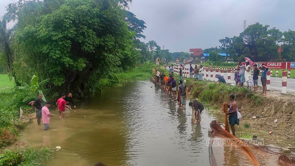 চট্টগ্রাম-কক্সবাজার মহাসড়কের চন্দনাইশের সড়কে পাশে পানি বেড়ে যাওয়ায় স্থানীয়রা জাল দিয়ে মাছ ধরছেন।&nbsp;ছবি: মাহমুদ জামান অভি