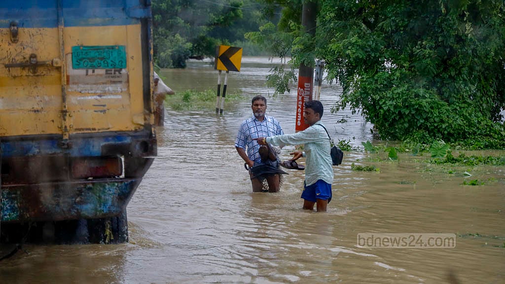 চট্টগ্রাম-কক্সবাজার মহাসড়কের চন্দনাইশের হাশিমপুর এলাকায় সড়কে হাঁটুর উপরে পানি, তার মধ্য দিয়ে হেঁটে যাচ্ছে মানুষ।&nbsp;ছবি: মাহমুদ জামান অভি