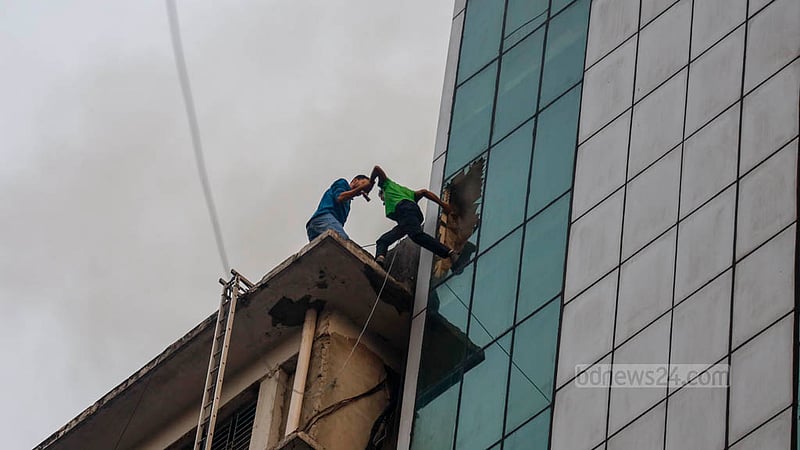 মহাখালীর আমতলীতে খাজা টাওয়ারে বৃহস্পতিবার আগুন লাগার পর দেয়ালের কাচ ভেঙ্গে পাশের ভবনে যাচ্ছেন কয়েকজন।&amp;nbsp;ছবি: মাহমুদ জামান অভি