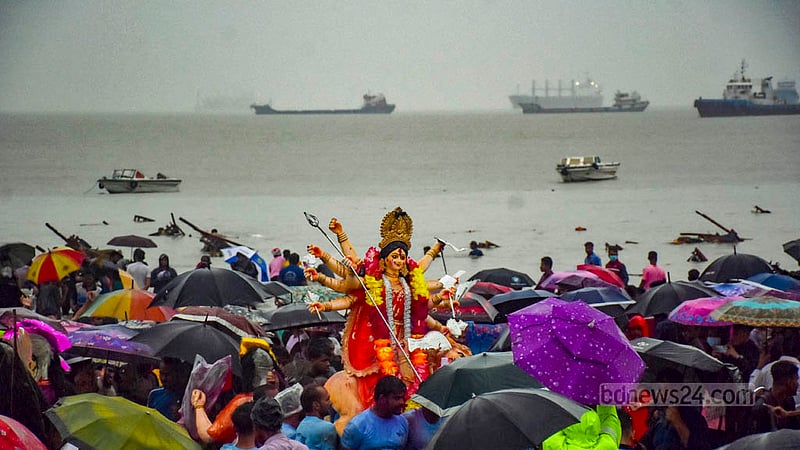 বৃষ্টির মধ্যে ছাতা হাতে পতেঙ্গা সমুদ্র সৈকতে দেবী দুর্গার প্রতিমা বিসর্জন।&amp;nbsp;ছবি: সুমন বাবু
