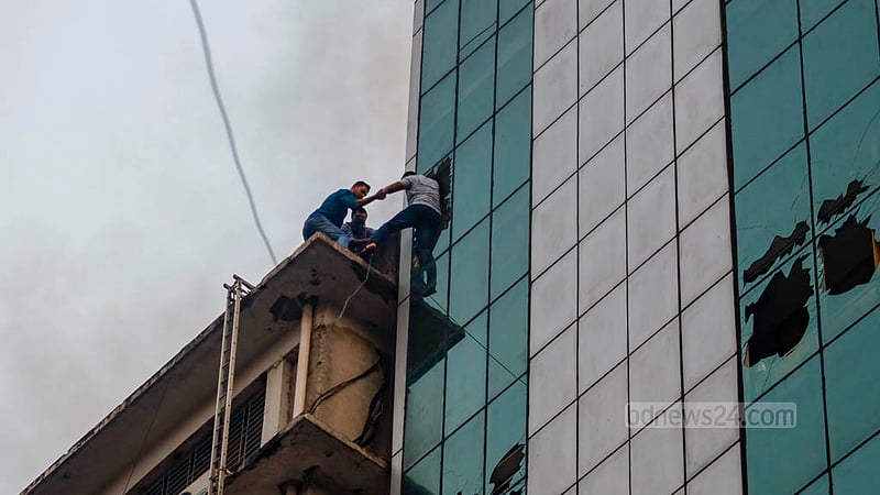 মহাখালীর আমতলীতে খাজা টাওয়ারে বৃহস্পতিবার আগুন লাগার পর দেয়ালের কাচ ভেঙ্গে পাশের ভবনে যাচ্ছেন কয়েকজন।&amp;nbsp;ছবি: মাহমুদ জামান অভি