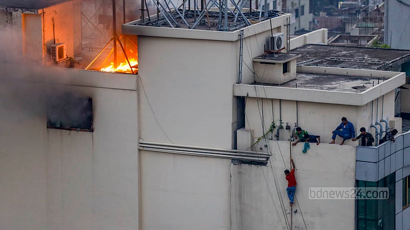 মহাখালীর আমতলীতে খাজা টাওয়ারে বৃহস্পতিবার আগুন লাগার পর ছাদ থেকে দড়ি বেয়ে নামছে মানুষ; পাশেই ছাদের উপরে জ্বলছে আগুন।&amp;nbsp;ছবি: মাহমুদ জামান অভি