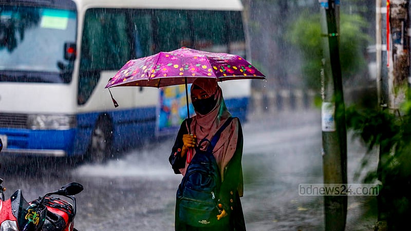ঢাকার শহীদ ক্যাপ্টেন এম মনসুর আলী এভিনিউতে সোমবার দুপুরে বৃষ্টির মধ্যে ছাতা হাতে এক নারী।&amp;nbsp;ছবি: মাহমুদ জামান অভি