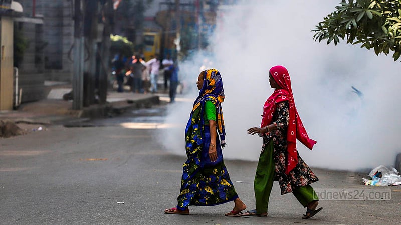 ঢাকার মিরপুর ১১ নম্বরে বৃহস্পতিবার পোশাক শ্রমিকদের লক্ষ্য করে পুলিশের ছোড়া কাঁদুনে গ্যাসের শেলের পাশ দিয়ে হেঁটে যাচ্ছেন দুই নারী।&amp;nbsp;ছবি: তাওহীদুজ্জামান তপু