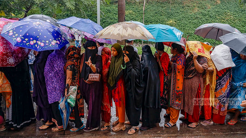 কারো হাতে ছাতা, কারো মাথায় বাজারের ব্যাগ; বৃহস্পতিবার ঢাকার হাতিরঝিলের মধুবাগ অংশে বৃষ্টির মধ্যে টিসিবির ট্রাক থেকে পণ্য কেনার জন্য অপেক্ষায় তারা।