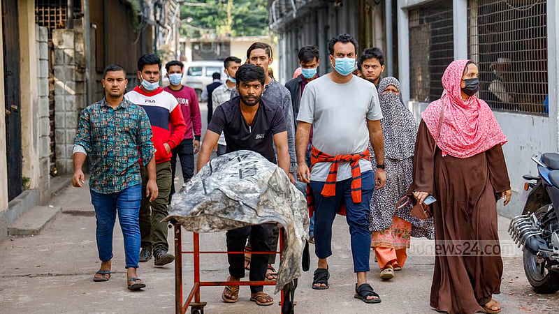 ঢাকা মেডিকেল কলেজ হাসপাতালের মর্গে নেওয়া হচ্ছে মোহনগঞ্জ এক্সপ্রেস ট্রেনের আগুনে দ্গ্ধ নাদিরা আক্তার পপি ও তার ছেলে ইয়াসিনের মরদেহ; পেছনে স্বজনরা।