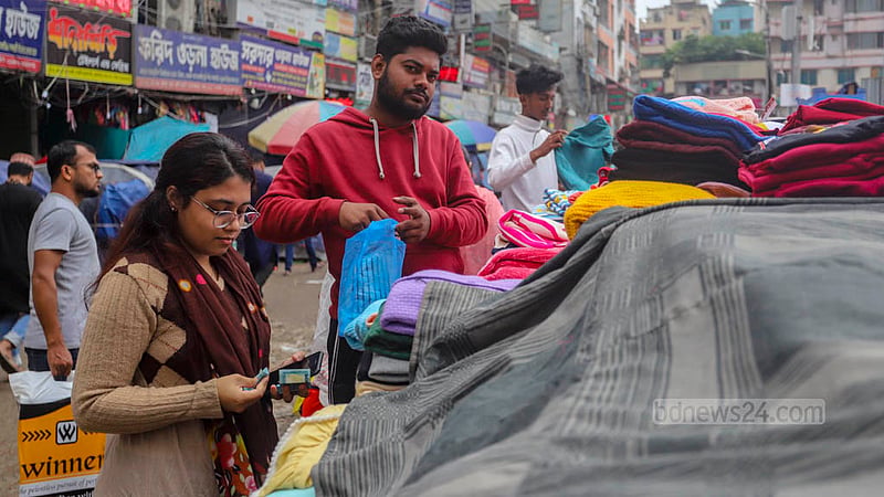 ঢাকার মোহাম্মদপুরে কৃষি মার্কেটে চকি থেকে গরম কাপড় কিনছেন এ নারী।