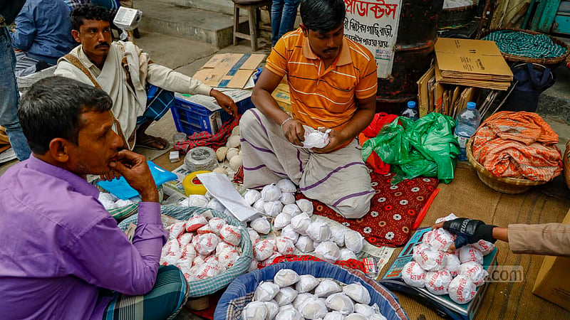 মানিকগঞ্জের ঝিটকা বাজারে বিক্রির জন্য পাল্লায় মাপা হচ্ছে হাজারী গুড়।