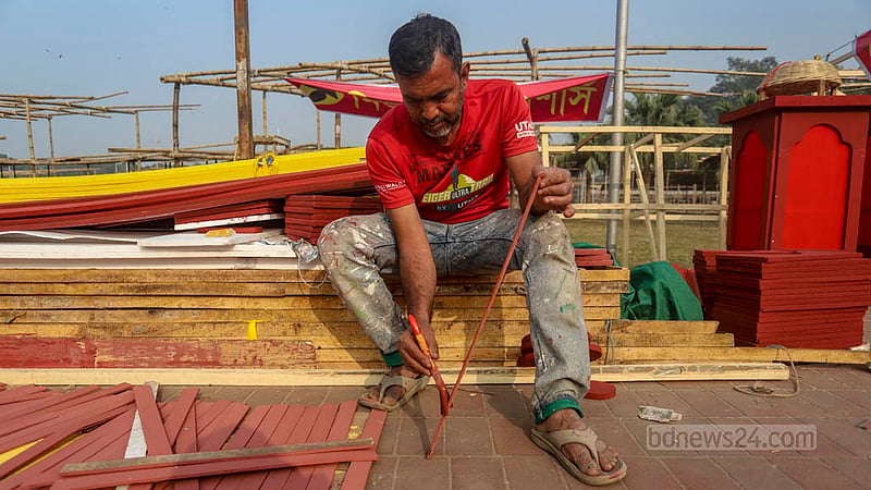 ঢাকার সোহরাওয়ার্দী উদ্যানে একুশে বইমেলার স্টলে রং করছেন এ শ্রমিক।