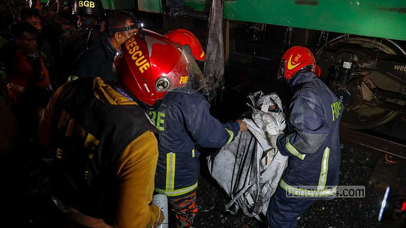 শুক্রবার রাতে রাজধানীর গোপীবাগে আগুনে পুড়ে যাওয়া বেনাপোল এক্সপ্রেস ট্রেনের একটি কোচ থেকে একজনের মরদেহ বের করে নিয়ে আসেন ফায়ার সার্ভিসের কর্মীরা।