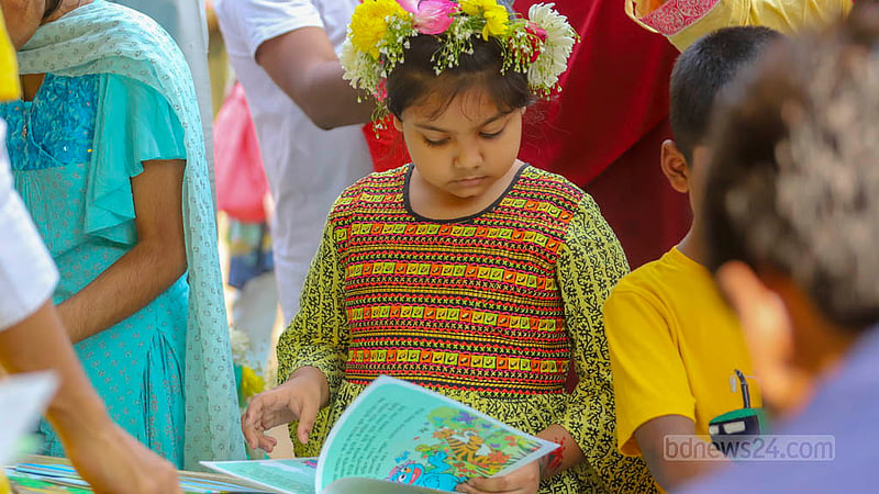 একুশে বইমেলার শিশুচত্বরে শুক্রবার বাসন্তী সাজে আসা শিশুরা স্টলে বই দেখছে।