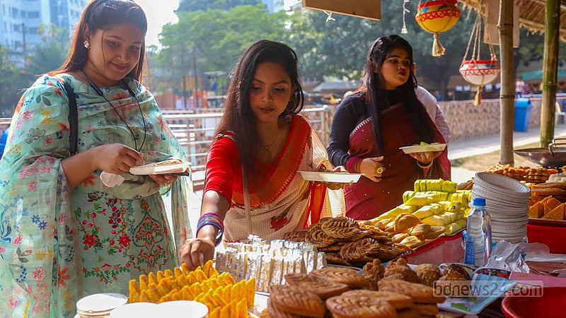 শিল্পকলা একাডেমিতে জাতীয় পিঠা উৎসবের একটি স্টল থেকে পিঠা কিনছেন তরুণীরা।