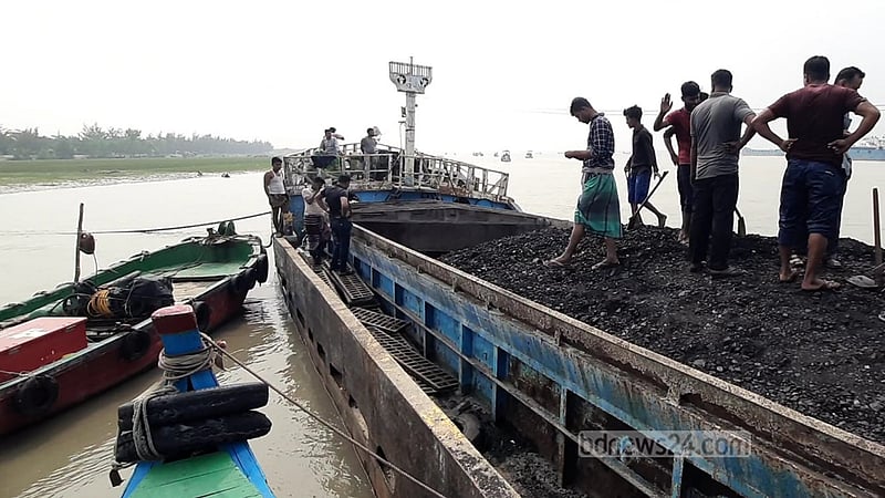কয়েকজন শ্রমিক কয়লা সরিয়ে রাখার জন্য বার্জের অপেক্ষায় দাঁড়িয়ে রয়েছেন।