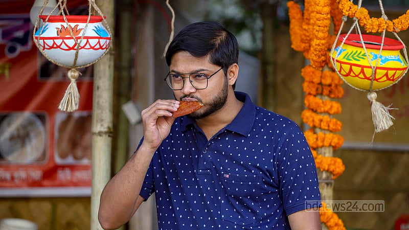 শিল্পকলা একাডেমিতে জাতীয় পিঠা উৎসবে শনিবার ঘুরতে এসে পিঠার স্বাদ নিচ্ছেন এক তরুণ।