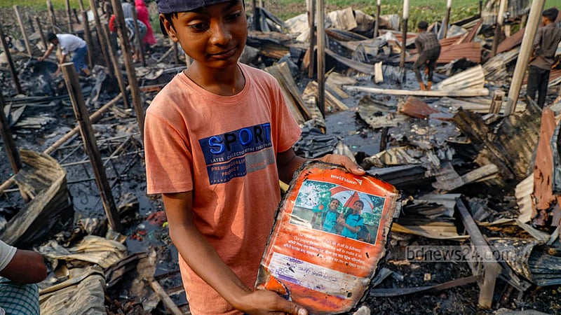 মিরপুর ১২ নম্বরে ঝিলপাড় বস্তির পুড়ে যাওয়া ঘর থেকে নিজের পোড়া বই বের করে নিয়ে আসছে চতুর্থ শ্রেণির শিক্ষার্থী আলিফ মোল্লা।