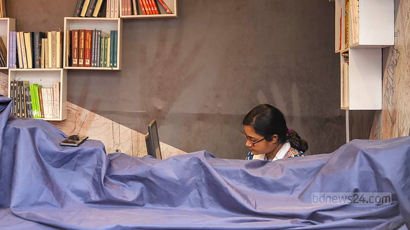 বৃষ্টির পানি থেকে রক্ষা পেতে পলিথিন দিয়ে বই ঢাকেন দোকানিরা।