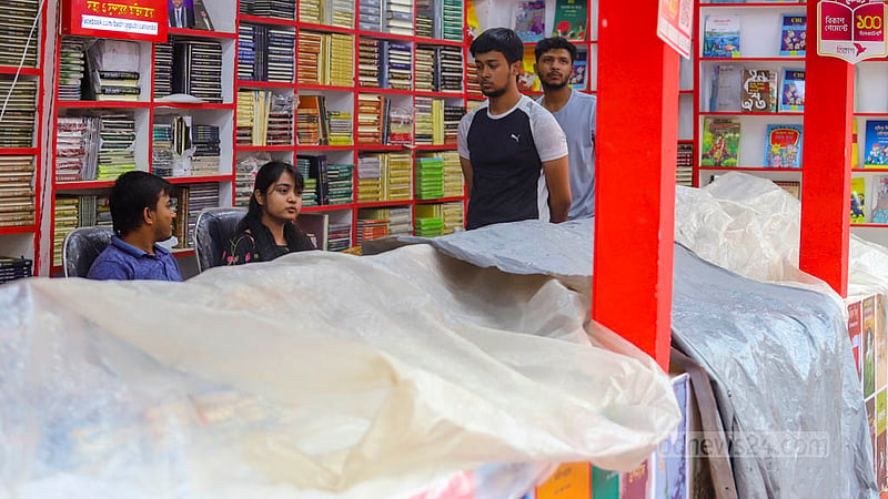 বৃষ্টির পানি থেকে রক্ষা পেতে পলিথিন দিয়ে বই ঢাকেন দোকানিরা।