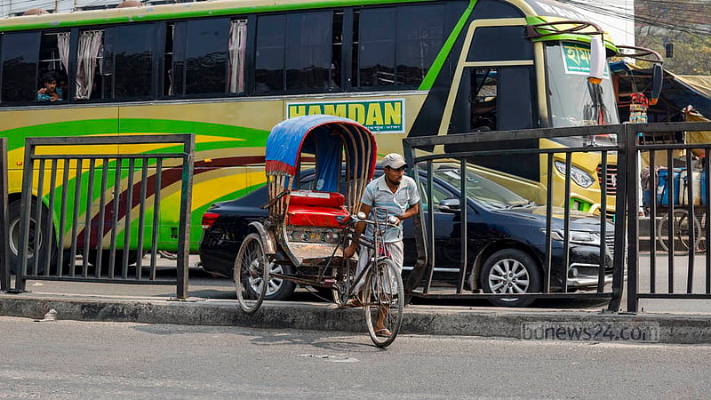 ঢাকার ব্যস্ত রামপুরা সেতুর বিভাজকের উপর দিয়ে রিকশা নিয়ে পার হচ্ছেন এক চালক।