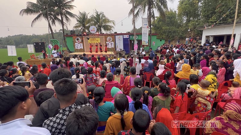 খোলা মঞ্চের সামনে কয়েকশ মানুষ অনুষ্ঠান উপভোগ করেন।