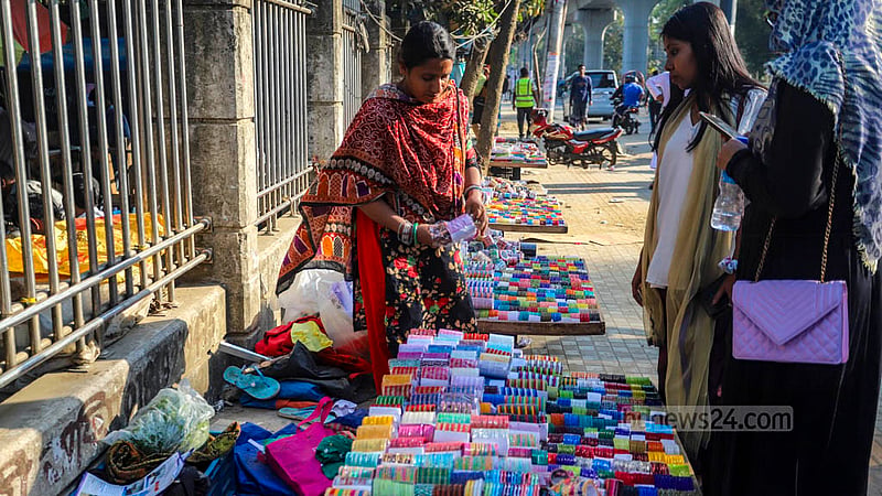 ঢাকা বিশ্ববিদ্যালয় এলাকায় নারী বিক্রেতাদের কাছে কাচের চুরি দেখছেন ক্রেতারা।
