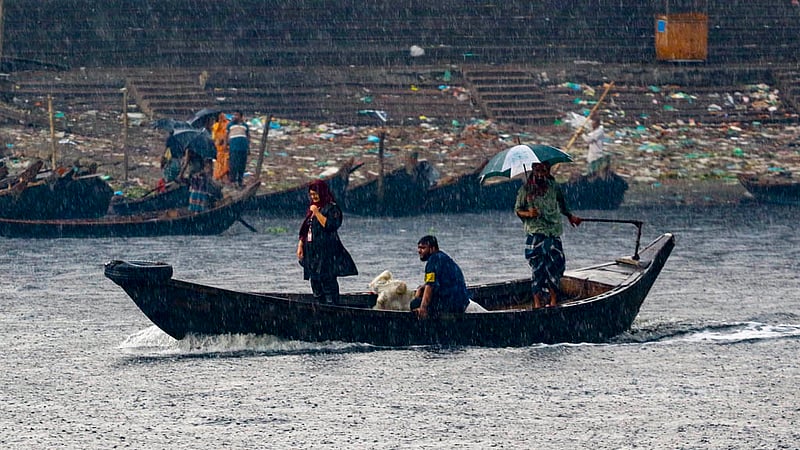 এক হাতে ছাতা, অন্য হাতে দাঁড়- বৃষ্টির মধ্যে মঙ্গলবার বিকালে খেয়া পারাপারে এক মাঝি।