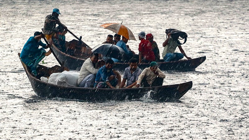 কেউ ছাথা মাথায়, কেউবা অন্যের ছাতার নিচে আশ্রয় নিয়ে মঙ্গলবার বৃষ্টির মধ্যে পার হন নদী।