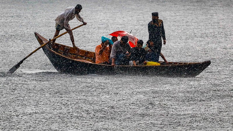 ঢাকার সদরঘাটে মঙ্গলবার বিকালে বৃষ্টির মধ্যে নদী পার হন অনেকে।