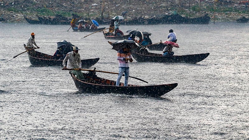 চৈত্রের শুরুতেই মঙ্গলবার বিকালে বৃষ্টি মাথায় বুড়িগঙ্গা নদী খেয়া দিয়ে পাড়ি দেন অনেকেই।