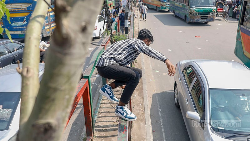 ঢাকার নিউ মার্কেটে এলাকায় সড়ক বিভাজকের উপর দিয়ে মঙ্গলবার দুপুরে লাফিয়ে রাস্তা পার হচ্ছেন এক তরুণ।