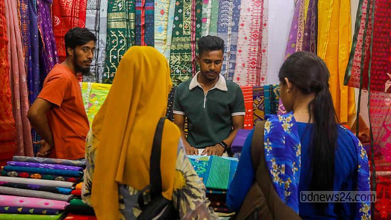 জাতীয় জাদুঘরের নলিনীকান্ত ভট্টশালী আর্ট গ্যালারিতে বুধবার জামদানি মেলার শেষ দিন একটি স্টলে শাড়ি দেখছেন দুই নারী।