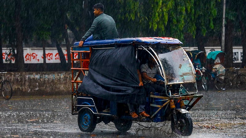 ঢাকা বিশ্ববিদ্যালয় এলাকায় মঙ্গলবার বিকালে ঝুম বৃষ্টির মধ্যে অটোরিকশার উপরে উঠে তা উপভোগ করেন একজন।