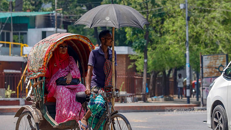 রোদ থেকে মাথা বাঁচাতে রিকশার সামনে বসানো হয়েছে ছাতা। অনেক চালকই গরমের সময় বেছে নিয়েছেন এ উপায়।