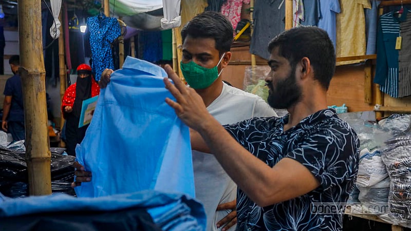 বঙ্গবাজারে বুধবার দুপুরে একজন ক্রেতাকে পোশাক দেখাচ্ছেন দোকানি।