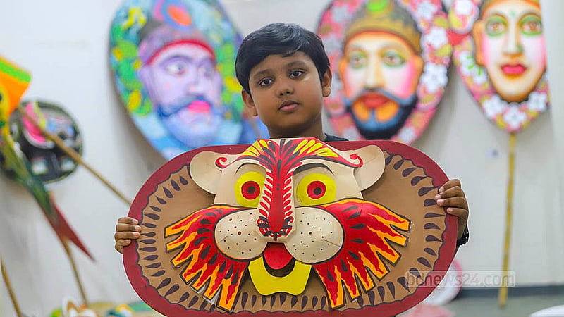 ঢাকা বিশ্ববিদ্যালয়ের চারুকলা অনুষদে কাগজের তৈরি মুখোশ হাতে এক শিশু