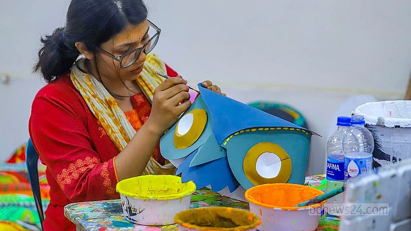 পহেলা বৈশাখ উদযাপনে ঢাকা বিশ্ববিদ্যালয়ের চারুকলা অনুষদে কাগজের তৈরি মুখোশে রঙ করছেন এক শিক্ষার্থী