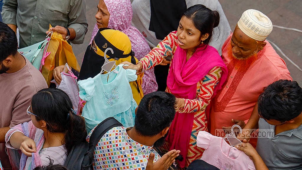ঢাকার নিউ মার্কেটে শুক্রবার দুপুরে ভিড়ের মধ্যে একটি দোকানে ছোটদের পোশাক দেখছেন এক নারী