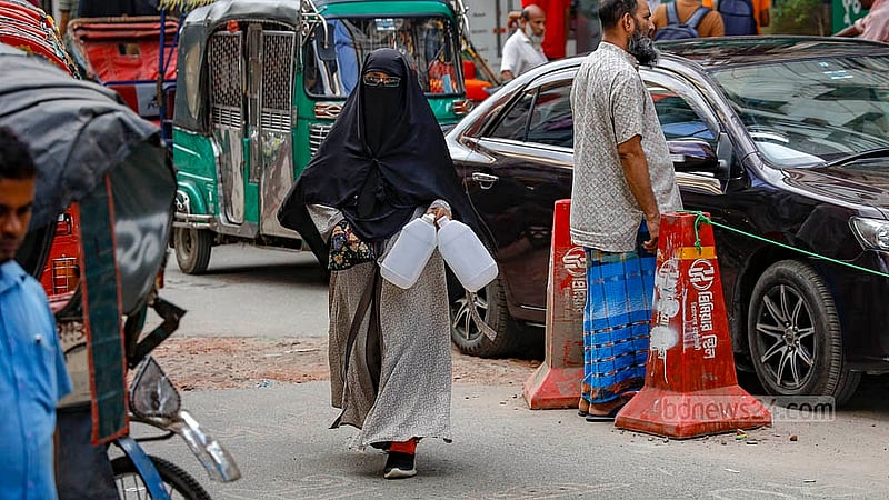 ঢাকার বনশ্রীতে বুথ থেকে পানি সংগ্রহ করতে প্লাষ্টিকের বোতল নিয়ে যাচ্ছেন এক নারী