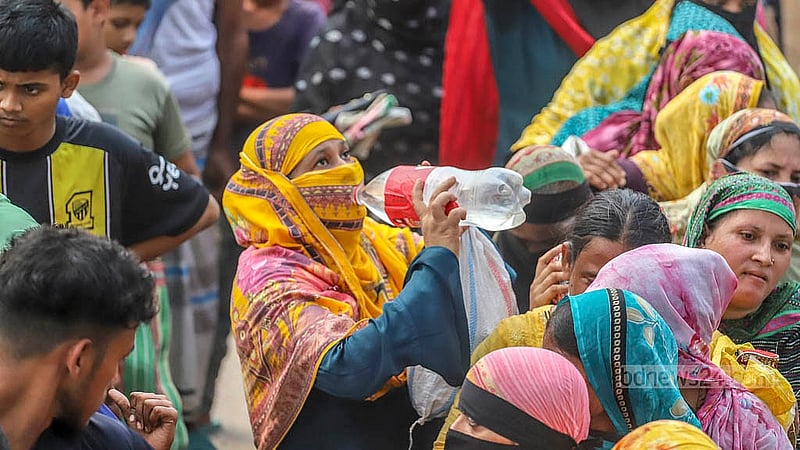 ঢাকার রায়েরবাগ এলাকায় টিসিবির পণ্যের জন্য দীর্ঘ সময় রোদের মধ্যে অপেক্ষায় থাকার সময় পানি পান করতে দেখা যায় অনেকে