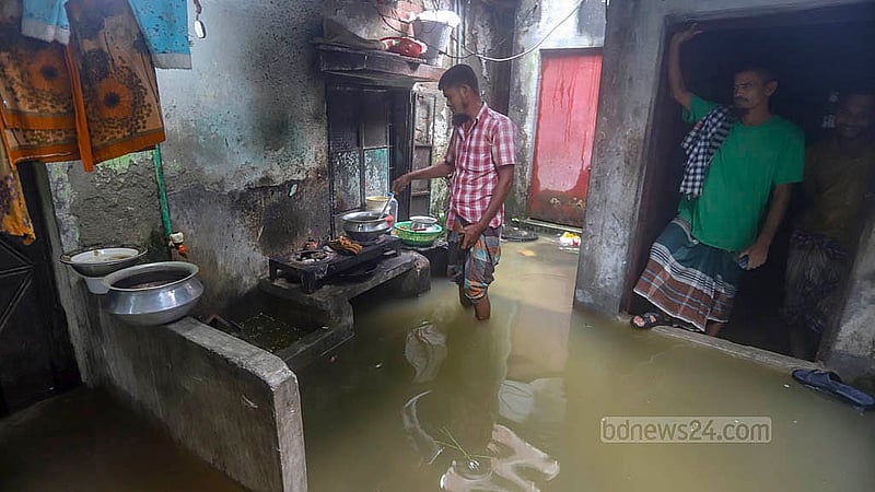 ডেমরার মুসলিম নগর এলাকায় বৃষ্টিতে সড়কের সঙ্গে তলিয়েছে নিচতলার বাসাবাড়ি। পানির মধ্যেই দাঁড়িয়ে রান্নার কাজ সারছেন অটোরিকশাচালক শরিফুল