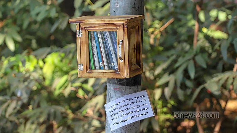 ধানমন্ডি লেকে চলাচলের রাস্তার পাশে গাছ কিংবা বিদ্যুতের খুঁটিতে রাখা ছোট ছোট বাক্সে বই পড়ার অভিনব এ উদ্যোগ অনেকের নজর কেড়েছে। যে কেউ চাইলে এখান থেকে বই নিয়ে পড়ে সময় কাটাতে পারেন