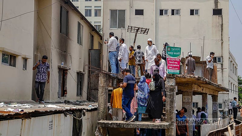 মাইলস্টোন স্কুল অ্যান্ড কলেজের যে ভবনে বিমান দুর্ঘটনা হয়েছিল, সেই ভবনের পেছনে দাঁড়িয়ে ঘটনাস্থল দেখছে মানুষ