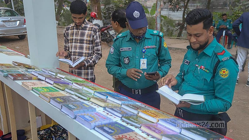 বাংলা একাডেমি প্রাঙ্গনে অমর একুশে বইমেলার একটি স্টলে বই দেখছেন দুই পুলিশ সদস্য
