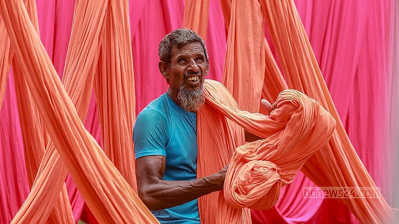 নারায়ণগঞ্জের ফতুল্লার হাজীগঞ্জ এলাকায় ডাইং কারখানায় রং করা কাপড় শুকানোর কাজ করছে এক শ্রমিক