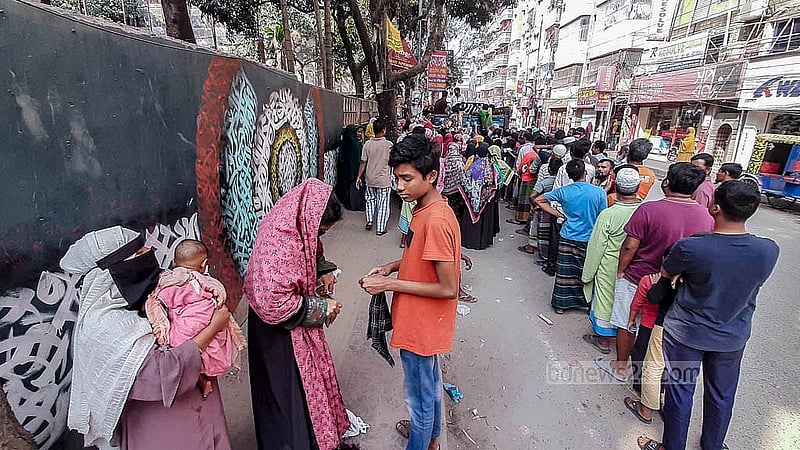 সন্তান কোলে নিয়ে টিসিবির পণ্য কিনতে আসেন এক নারী। কিন্তু প্রচণ্ড ভিড়ের কারণে সামনে যেতে পারেননি। বাধ্য হয়ে সবার পেছনেই দাঁড়িয়ে থাকতে দেখা যায় তাকে
