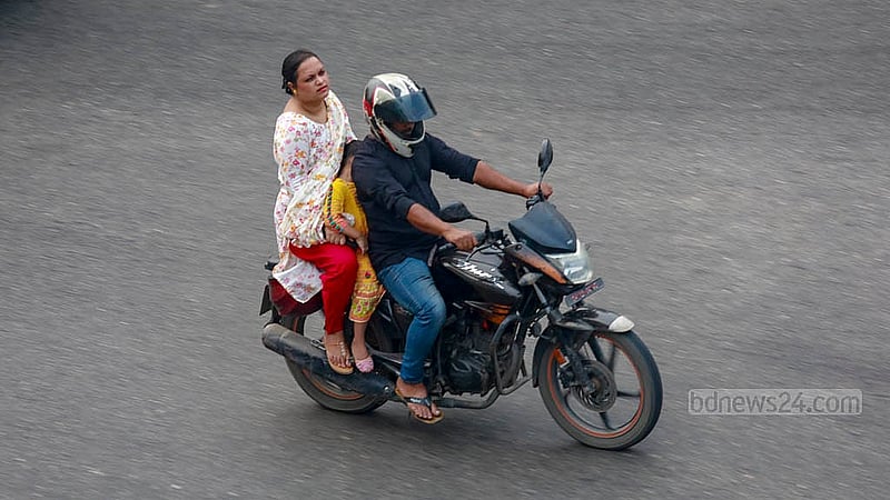 ঢাকার মগবাজার-মৌচাক ফ্লাইওভারের ব্যস্ত সড়কে মোটরসাইকেলের সামনে বসিয়ে নিয়ে যাওয়া হচ্ছে এক শিশুকে। চালকের মাথায় হেলমেট থাকলেও পেছনের আরোহী ও শিশুটির মাথায় নেই কোনো সুরক্ষা সরঞ্জাম