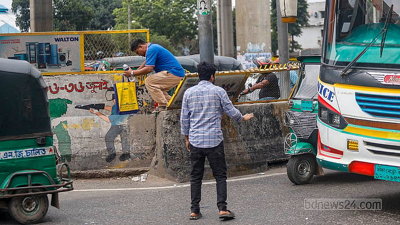 ঢাকার মহাখালীতে ঝুঁকি নিয়ে পারাপার ঠেকাতে সড়কের মাঝে দেওয়া হয়েছে উঁচু বিভাজক; উপরে আছে লোহার বেষ্টনী। ফুটব্রিজে না গিয়ে ঝুঁকি নিয়ে সেই লোহার বেষ্টনী টপকাচ্ছেন পথচারীরা