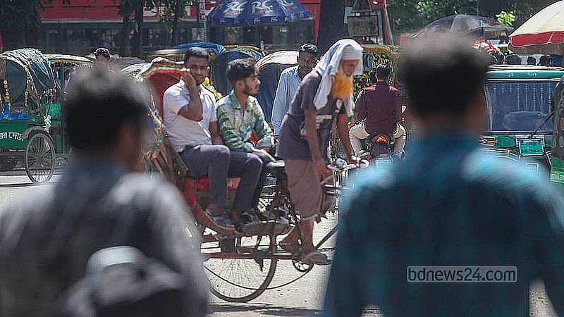 রোদের মধ্যে মাথায় গামছা পেছিয়েছেন এক চালক। সোমবার ঢাকা বিশ্ববিদ্যালয় এলাকায় তোলা