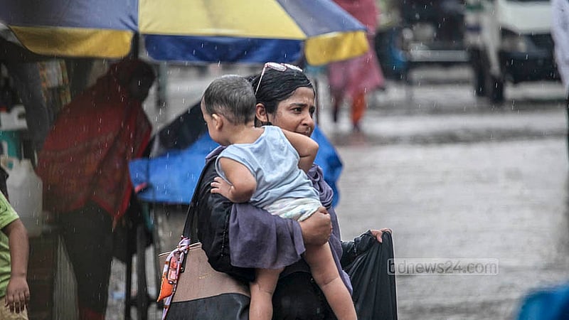 ঢাকার মুগদায় মঙ্গলবার বৃষ্টির মধ্যে সন্তান কোলে নিয়ে গন্ত্যেবের পথে এক নারী