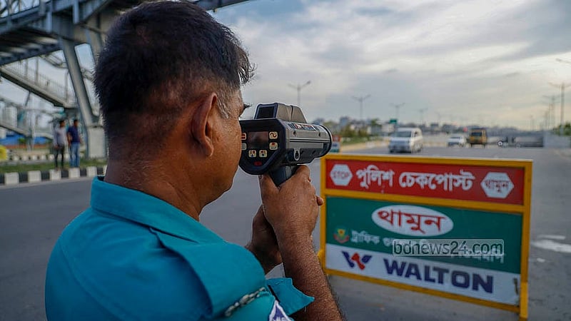 পূর্বাচল এক্সপ্রেসওয়েতে স্পিড গান দিয়ে গাড়ির গতি যাচাই করছেন এক ট্রাফিক পুলিশ সদস্য